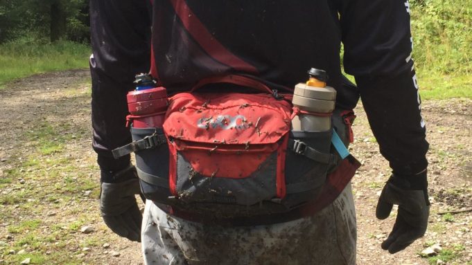 Mountain biker with the Hip Pack Pro 3L in carbon grey/chilli red around their waist