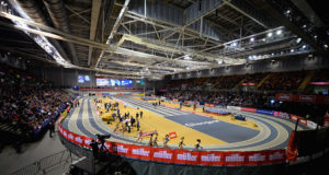 A panoramic shot of the indoor track at Glasgow with femal athletes sprinting around it