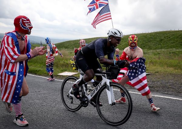People dressed as wrestlers cheer on a cyclist