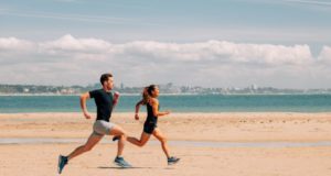 Male and female runners on a beach