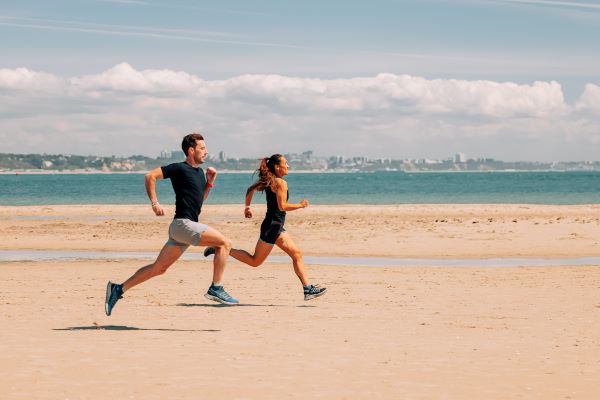Male and female runners on a beach