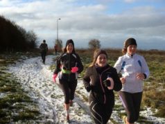 3 smiling women running in the snow