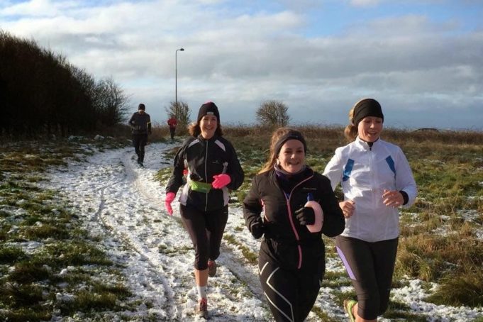 3 smiling women running in the snow