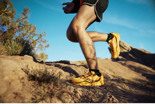 Image of man's legs, wearing yellow shoes, in a trail/dry dirt environment