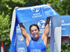 Eleonora Peroncini holds the blue finish tape aloft with a huge smile on her face