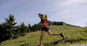 Runner running through a grassy, hilly landscape in sunshine