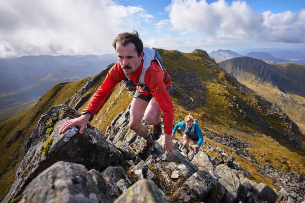 Man crests a rocky mountain summit