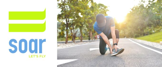 A runner in the road kneeling down holding their ankle. Sunshine in the backgground.