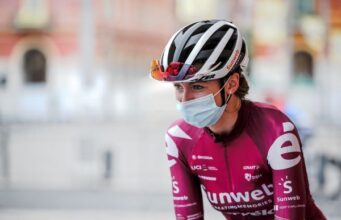Liane Lippert's upper half pictured. She wears a white cycling helmet, pink cycling jersey, and a face mask.