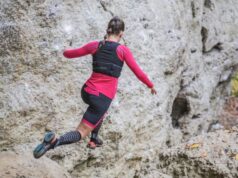 A female runner runs on a mountainous, rocky trail