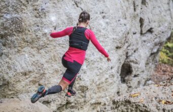 A female runner runs on a mountainous, rocky trail