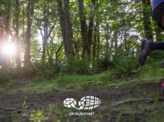 Two trail runners in woods with the sun shining through the trees