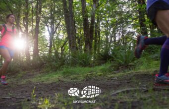 Two trail runners in woods with the sun shining through the trees