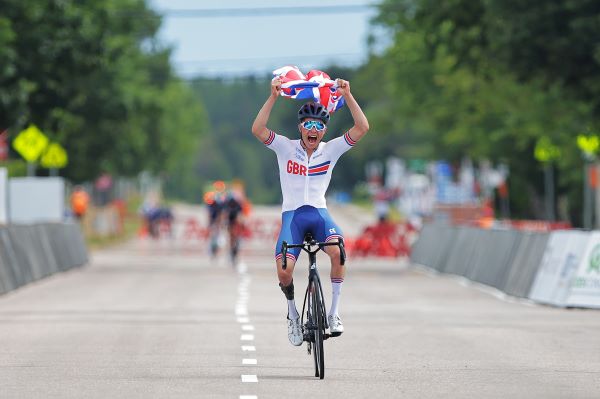 Fin Graham cycles while holding the union flag above his head with a look of pure joy on his face.