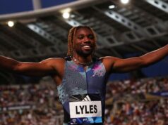 Noah Lyles raises his hands in the air to a packed stadium crowd