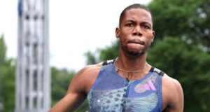 Zharnel Hughes head and torso, he is wearing a purple patterned vest and looks like he's just finished a race.