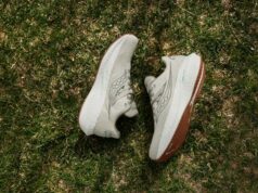 A pair of white/cream running shoes lie on grass