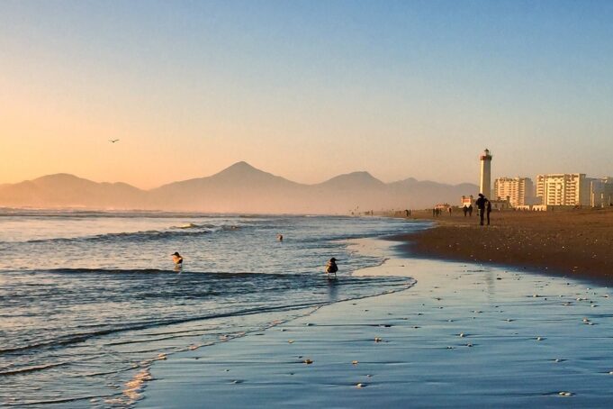 Dreamy image of the beach at sunset, with people paddling in the sea.