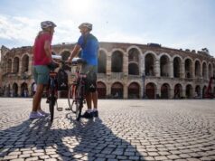 two cyclists stand in front of Verona arena