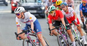 Female cyclist leads a peloton on a road bike