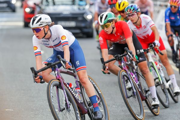 Female cyclist leads a peloton on a road bike