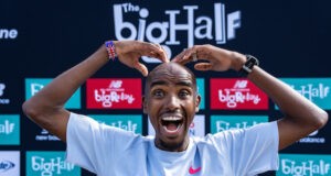 Mo Farah make an M sign with his hands above his head. he is smiling.