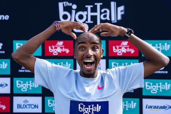 Mo Farah make an M sign with his hands above his head. he is smiling.