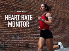 Woman in red vest and wearing watch runs past a brick wall. Text reads COROS Heart Rate Monitor