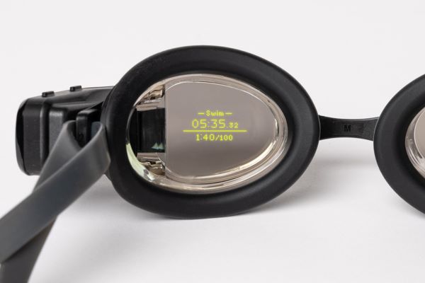 A swimming goggle lens with data displayed in yellow text on the goggle