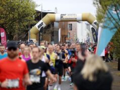 Runners in a road race, going underneath an inflatable gold gantry