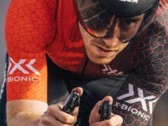 Close up of a male cyclist holding bike handlebars and wearing an orange and black t-shirt