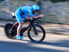 Female athlete in blue cycles fast on a road bike