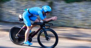 Female athlete in blue cycles fast on a road bike