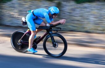 Female athlete in blue cycles fast on a road bike