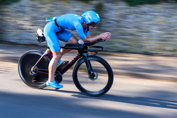 Female athlete in blue cycles fast on a road bike