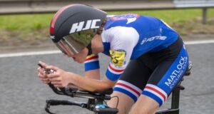 Female cyclist leans over aero bars on time trial bike