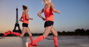 Two female runners dressed in orange run past the Eiffel Tower