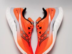 A pair of bright orange running shoes against a white background
