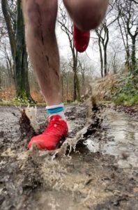 Red shoed foot lands in puddle creating a splash