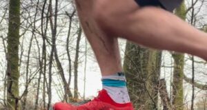 Red shoe-d foot runs over a large tree truck on its side