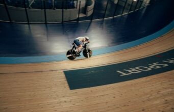 A lone cyclist on a black bike on an indoor track