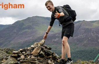 A man touches a cairn on top of a mountain summit