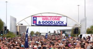 Thosands of runners in the start area of the Manchester Marathon. Banner above tyhem reads Welcome and Good Luck