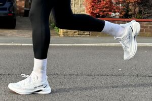 Legs and feet of a runner wearing black leggings and white running shoes