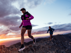 Woman and man run on a high mountanous landscape at sunrise