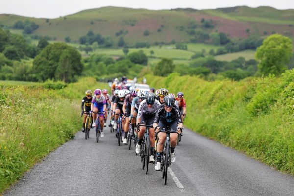 Peloton of female cyclists on a green country lane