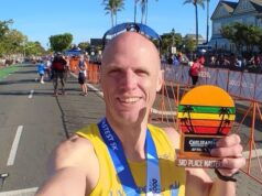 Man in yellow vest and sunglasses holds a medal which says 3rd Place masters