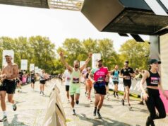 Runners cross the finish line with arms in the air