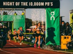Female athletes on a track run under a gantry with the wording Night of the 10,000M PB's