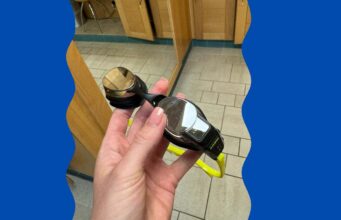 FORM smart goggles held in a persons hand in the changing room of the swimming baths.